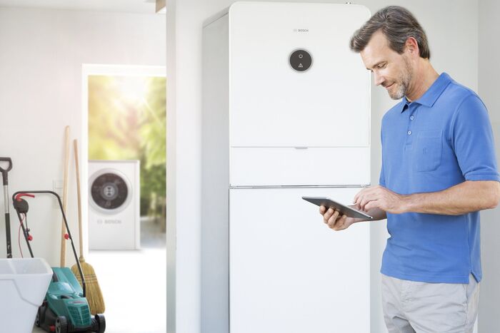 Mann mit Bosch Energiemanager steuert seine Haustechnik smart via Tablet.
