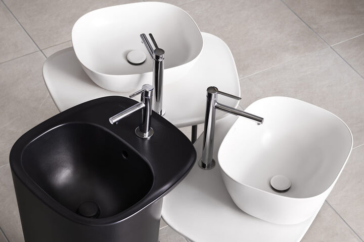Kombination aus Waschbecken von VitrA auf Plural Badmöbeln. Zwei weiße Aufsatzbecken werden von einem schwarzen Standwaschtisch flankiert.