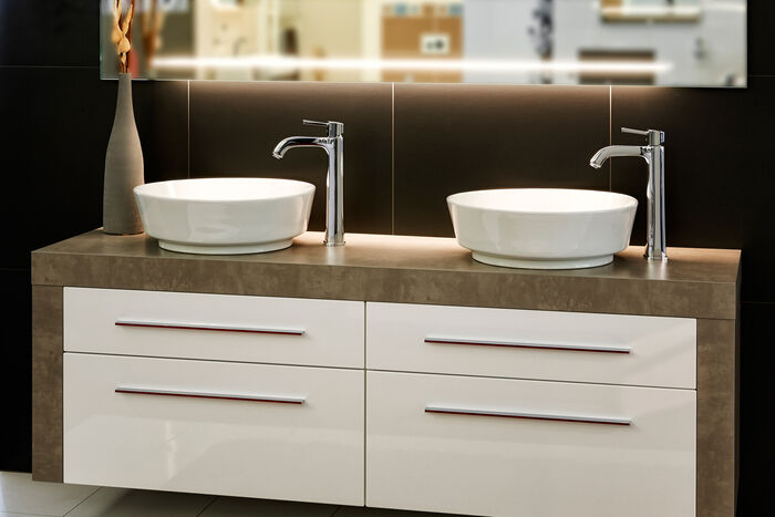 Waschbecken Standarmaturen chrom am Waschplatz mit zwei Waschschalen und Badmöbel in Holz und weiss.