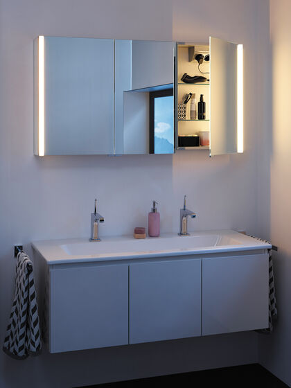 Doppelwaschbecken eingebaut. Darüber ein Spiegelschrank, geöffnet mit Warmlicht Beleuchtung.