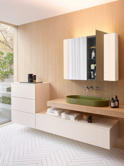 Helle Badmöbel und grünes Waschbecken, seitliche ansicht. Geöffneter Spiegelschrank. Serie rc40 von burgbad.