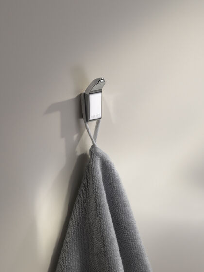 Handtuchhaken aus Chrom wandmontiert mit grauem Handtuch.