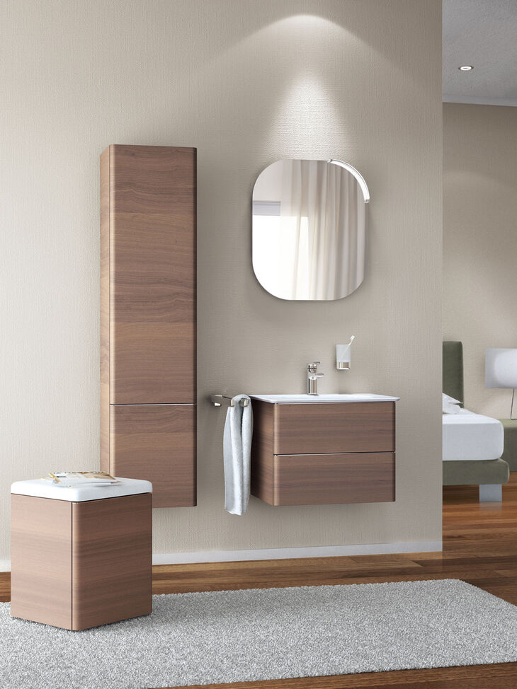 Ideal Standard Softmood Waschplatzsituation mit braunen Badmöbeln. Wandhängener Hochschrank und wandmontiertes Einbauwaschbecken, Hocker und Spiegel. Softmood von Ideal Standard
