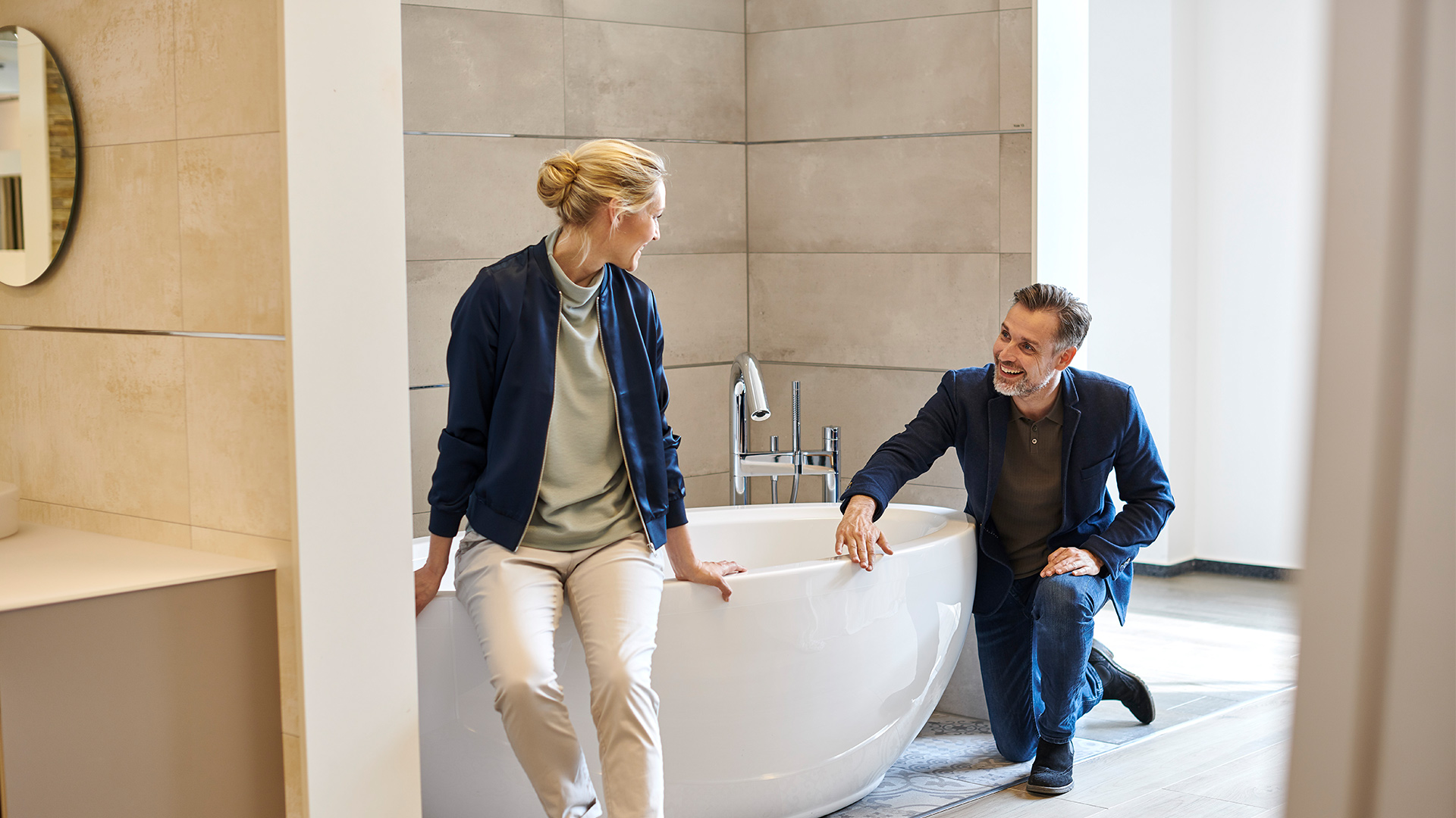 Kundenpaar nimmt eine freistehende Badewanne in Augenschein in einer Badausstellung.