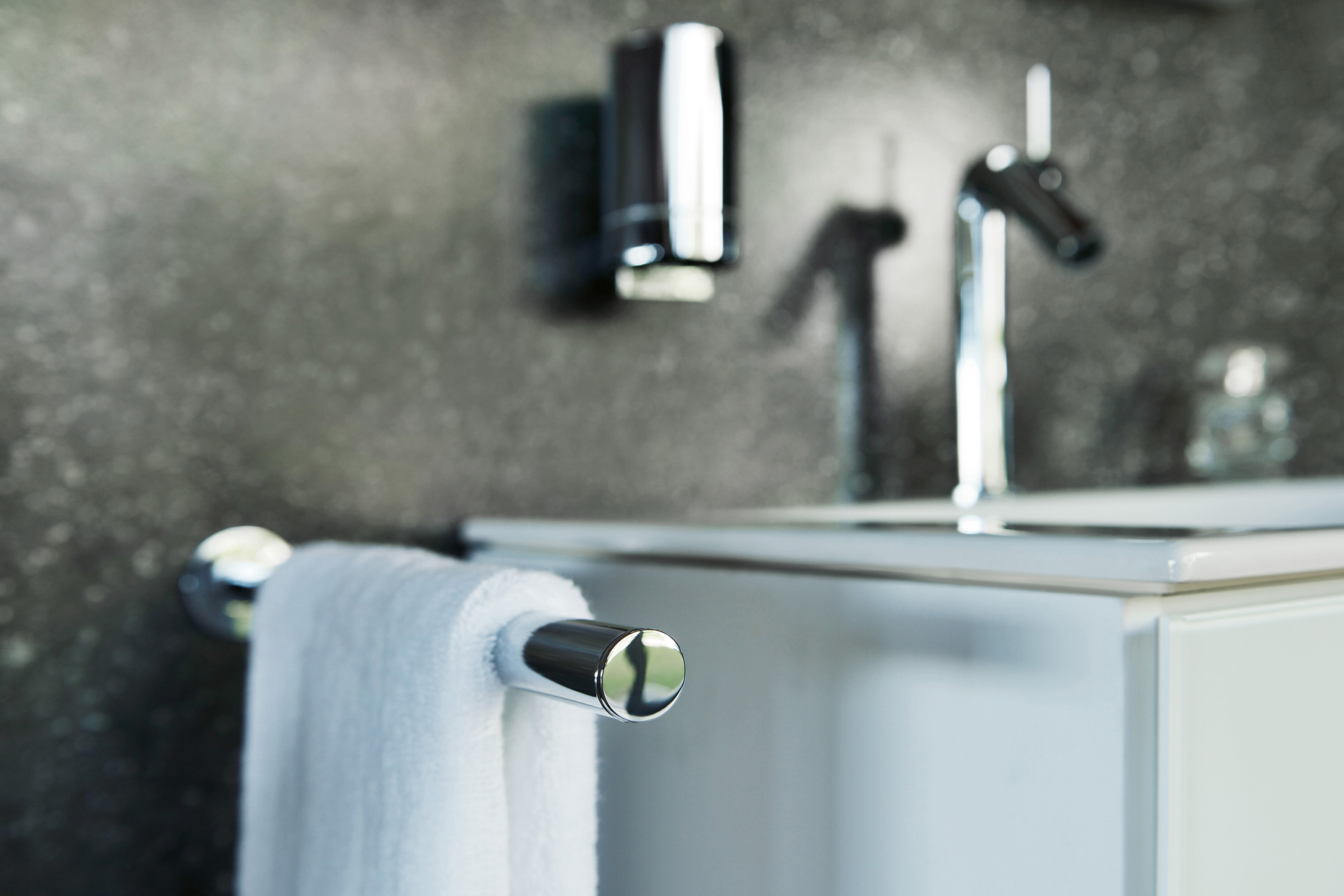 Handtuchhalterstange aus Chrom, Seigfenspender und einer Badarmatur am Waschbecken montiert.