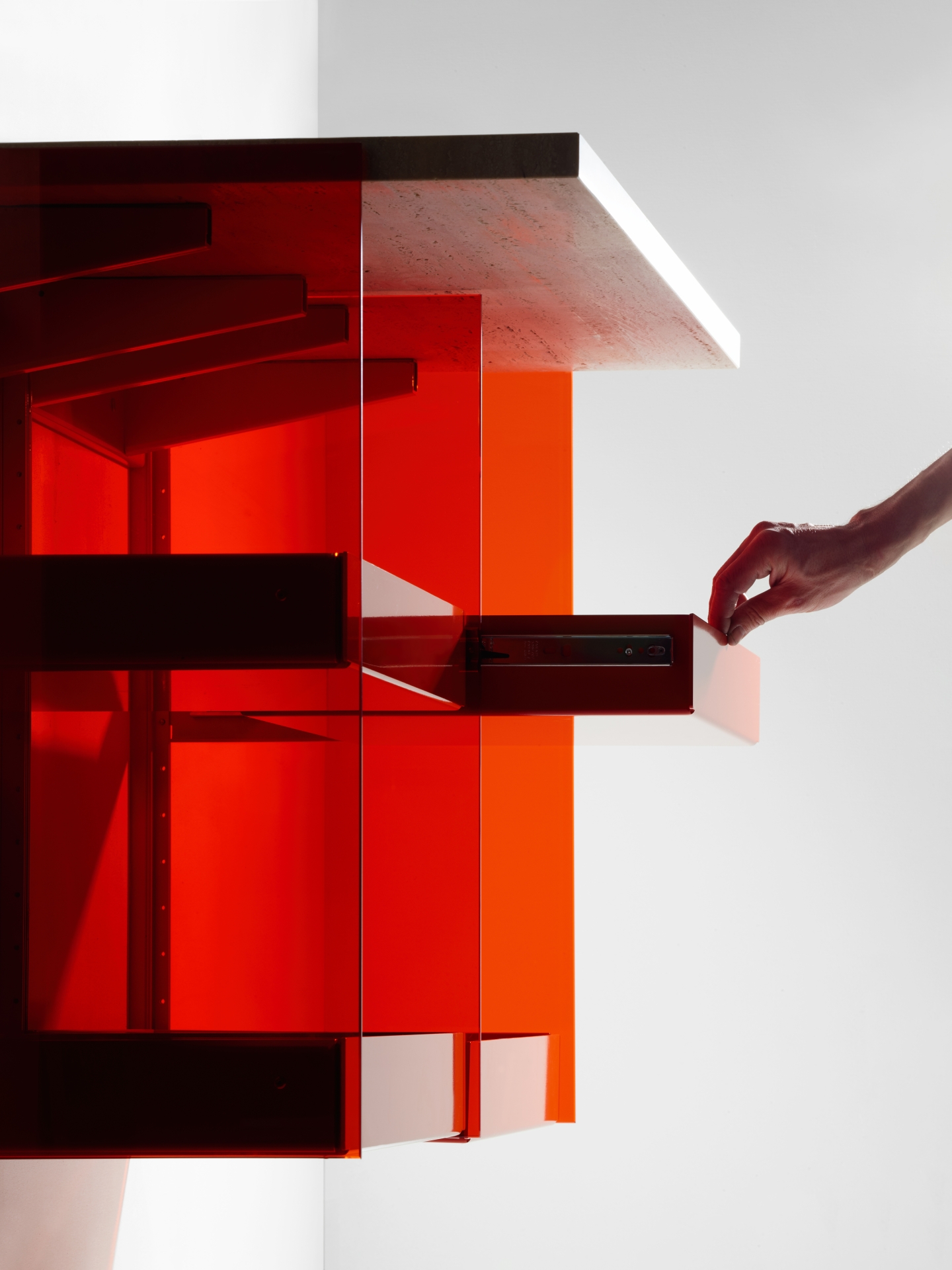 Transparentes Badezimmermöbel aus rotem Glas mit ausziehbaren Schubladen und Ablagefläche.
