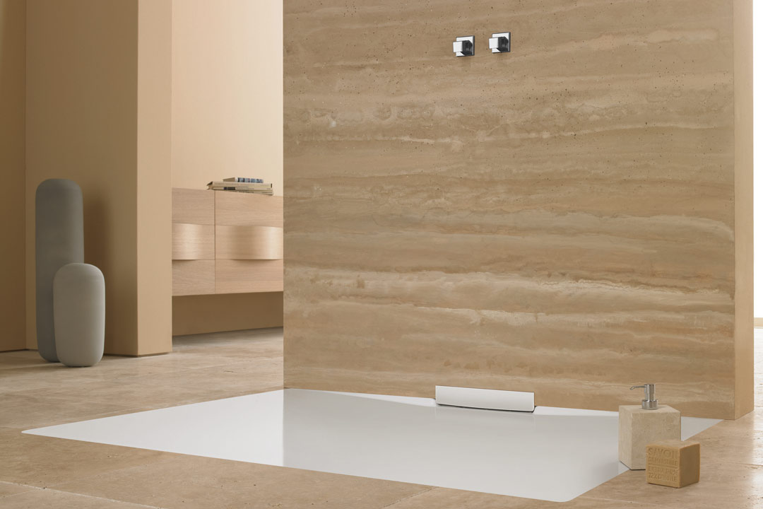 Braunes Badezimmer, in dem eine weiße bodenebene barrierefreie Kaldewei Metis Duschfläche eingelassen ist. Nebenan stehen Hygieneartikel.