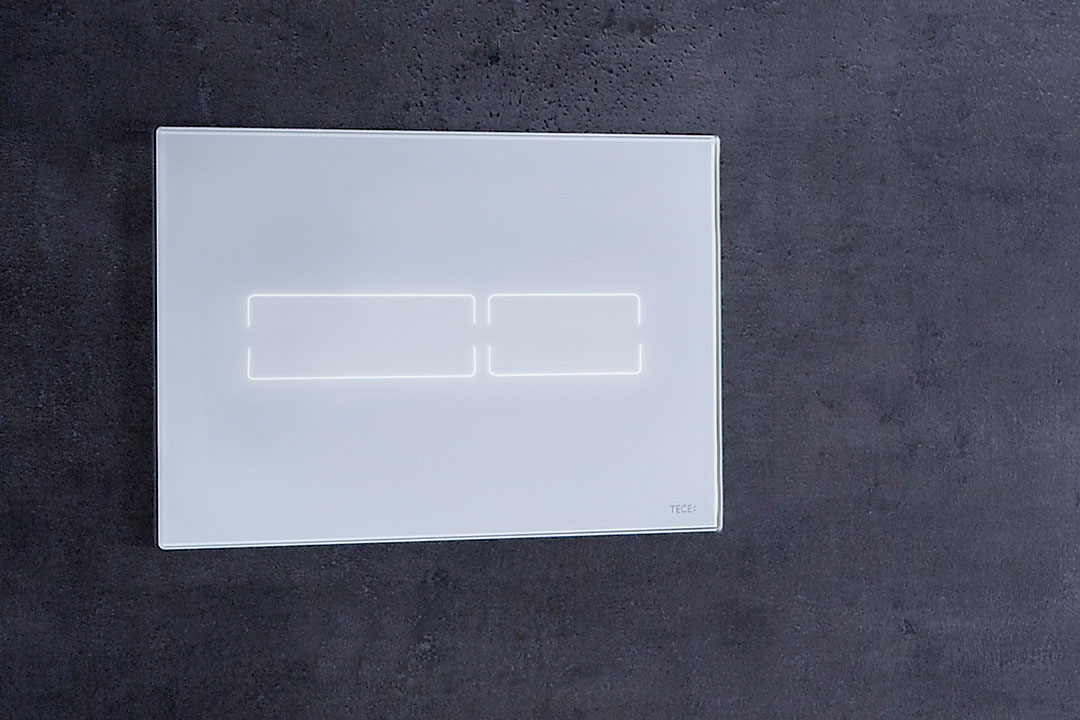 Großaufnahme der elektronischen Drückerplatte für WC-Spülung von TECElux, Ausführung in weißem Glas.