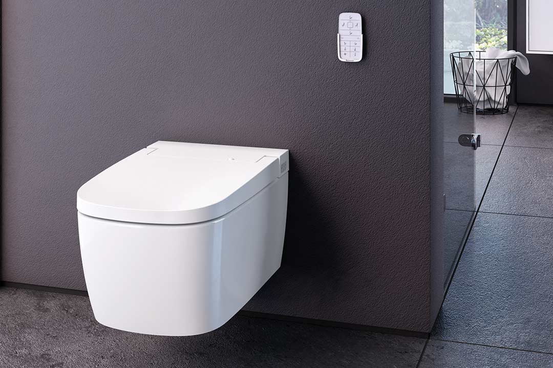 Elegantes Dusch-WC von VitrA der Modellreiche V-care. Abbildung in einem dunklen Milieu mit Fernbedienung, die an der Wand angebracht wurde.
