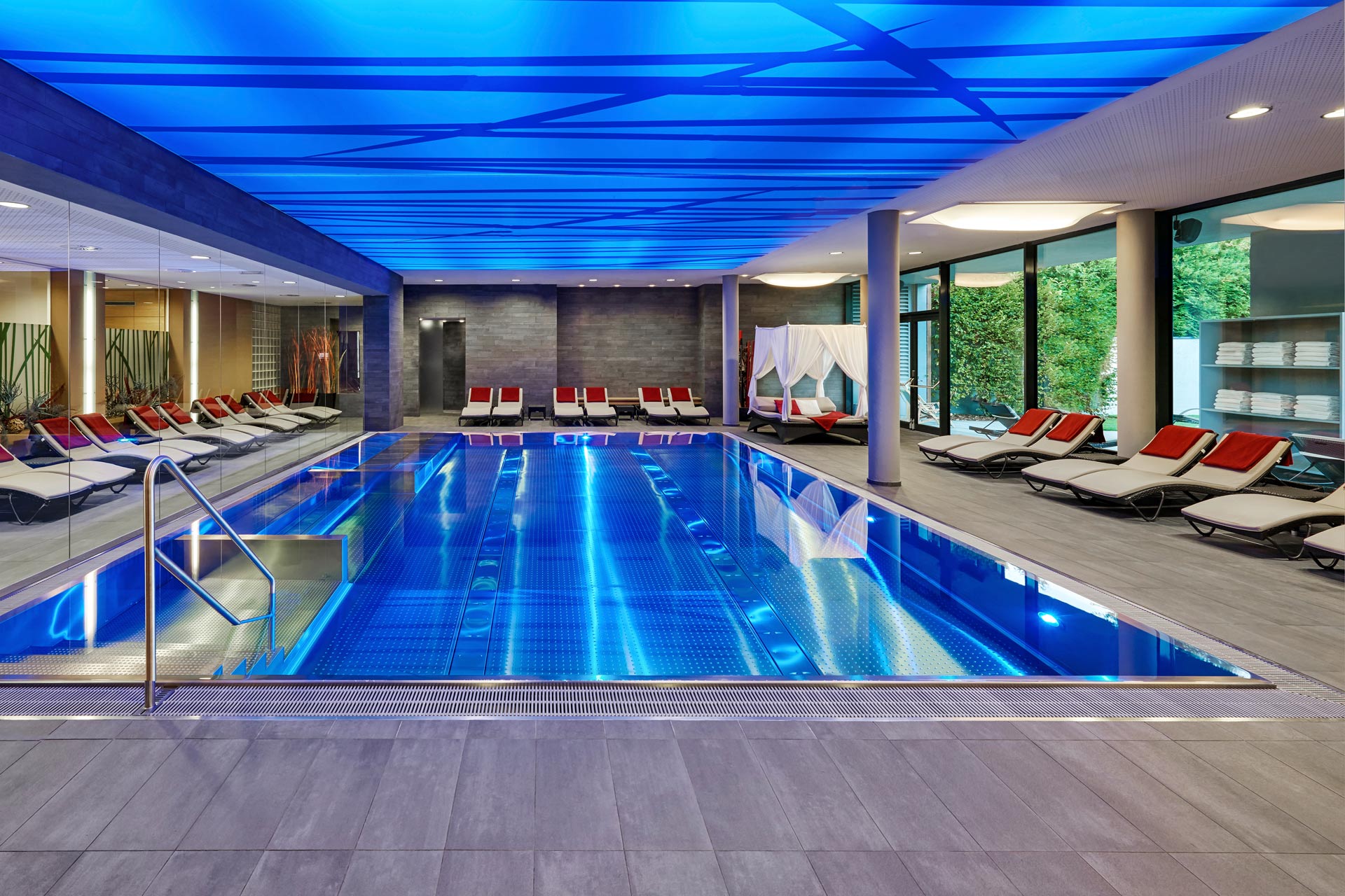 Pool im Hotel Ritzenhof. Blau beleuchtetes Wasser und Decke. Seitlich liegen zum Entspannen.